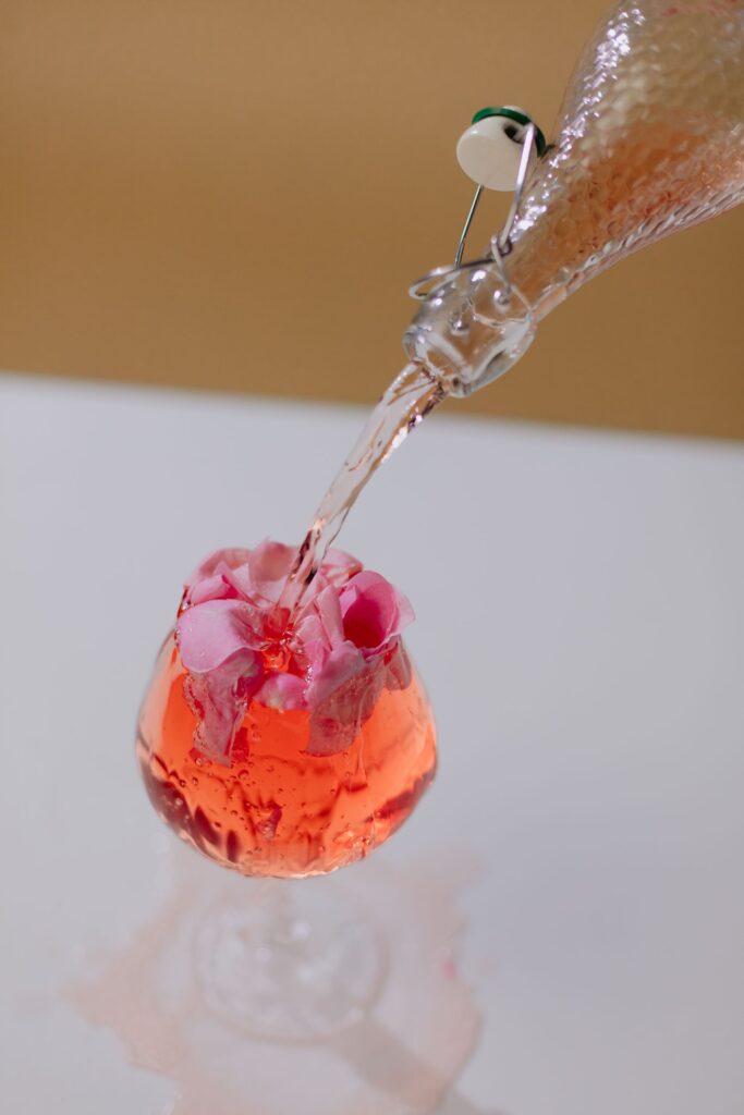 Pink flowers overflowing from a glass as more liquid is poured in, symbolizing emotional capacity and carrying too much.